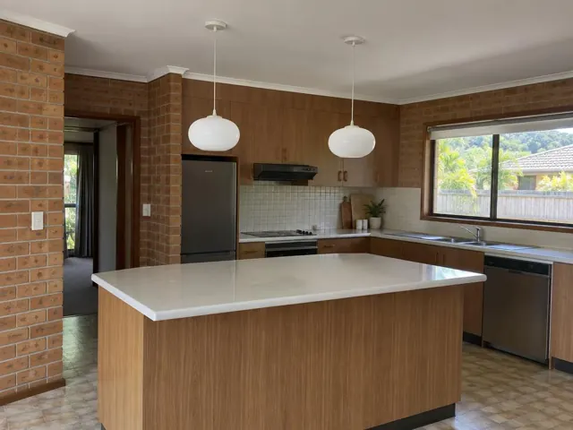 Kitchen with two pendant lights above a central island in a brick and timber home in Pacific Pines